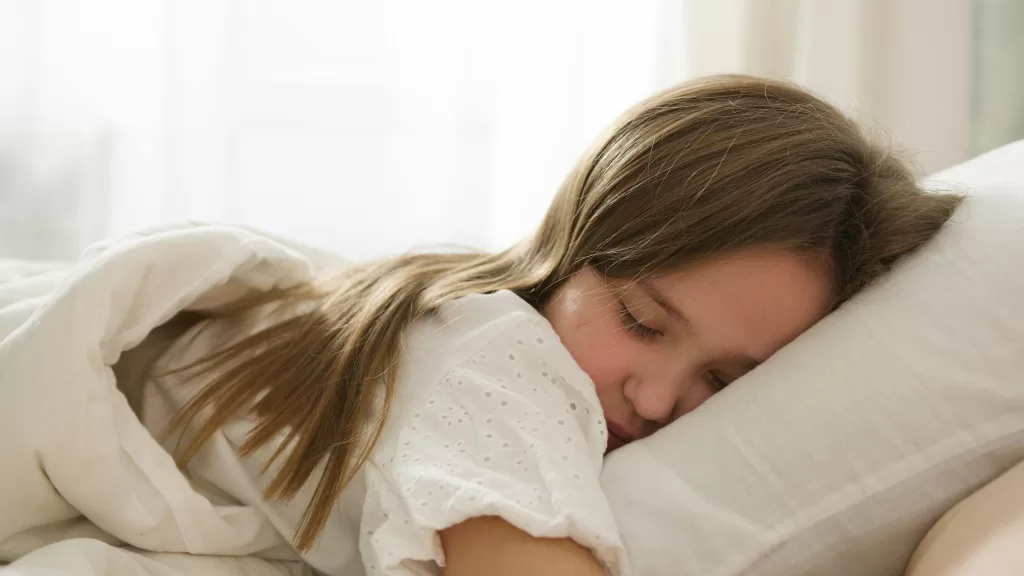 A young girl peacefully sleeping on a pillow, enveloped in soft light and comfort.